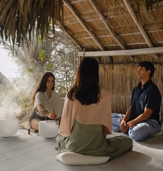 Wellness experience and sound healing meditation with crystal bowls under a traditional palapa at La Valise Tulum Hotel.