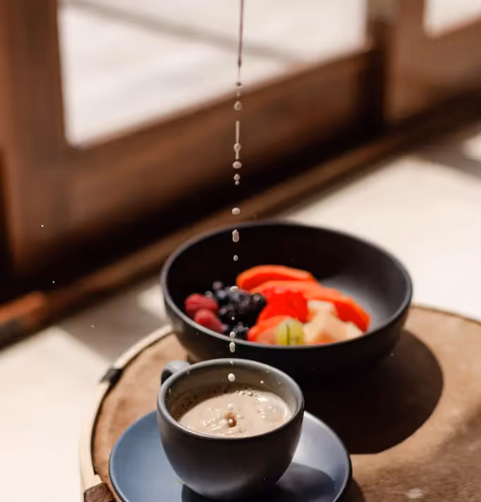 Healthy breakfast featuring fresh fruit bowl and coffee served on a terrace at La Valise Tulum Hotel.