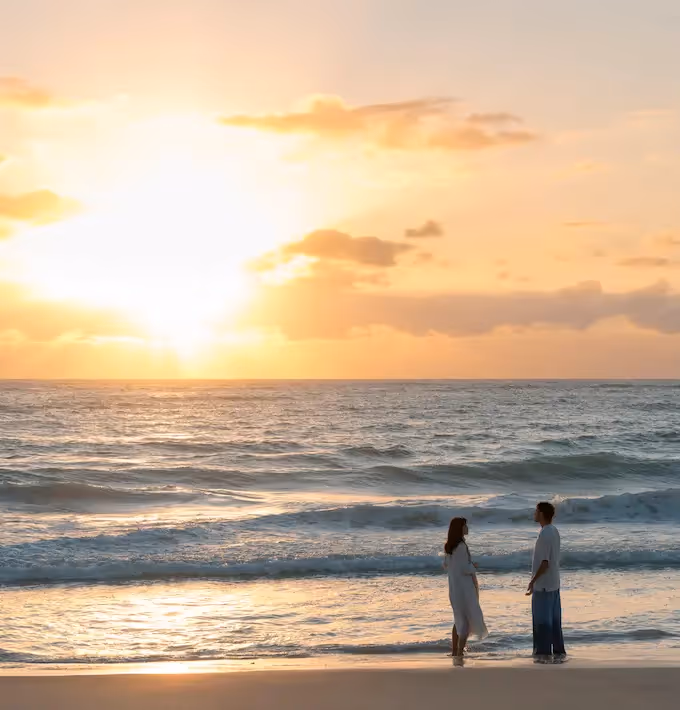 Couple walking on a white sand beach at sunset overlooking the Caribbean Sea at La Valise Tulum Hotel.