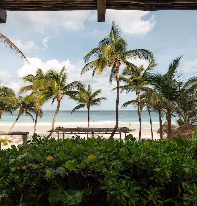 Stunning view of the white sand beach and palm trees from the terrace of La Valise Tulum Hotel.