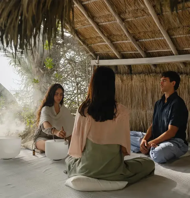 Wellness experience and sound healing meditation with crystal bowls under a traditional palapa at La Valise Tulum Hotel.