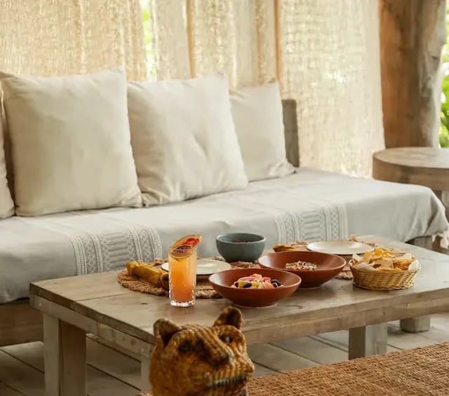 Selection of Mexican dishes and cocktails served on a wooden table in the lounge area of La Valise Tulum hotel.