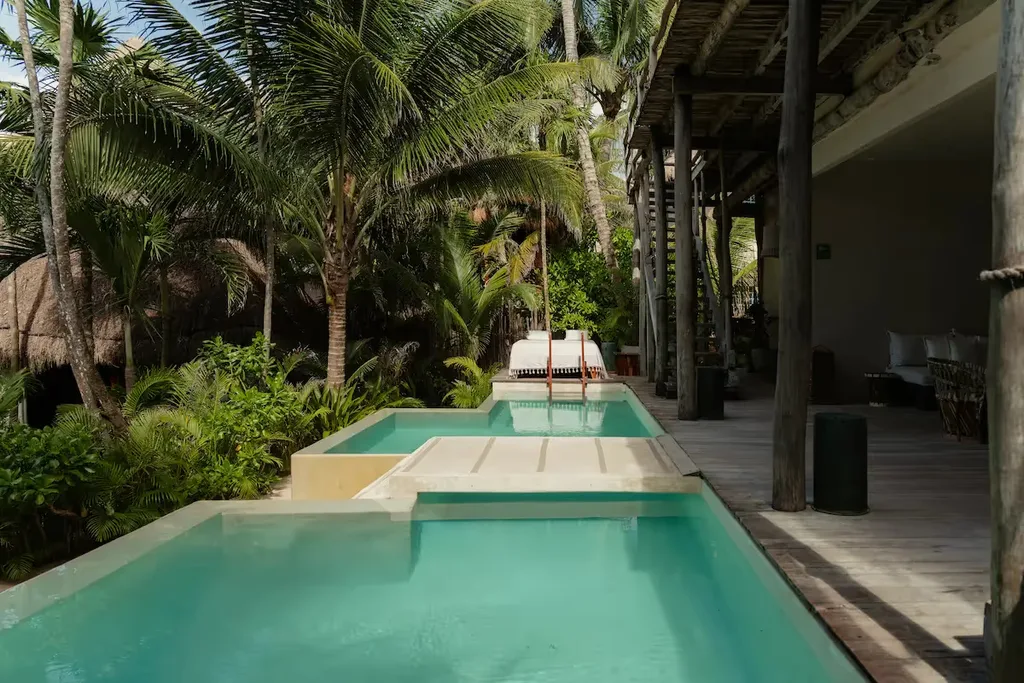 Piscina infinita privada rodeada de palmeras tropicales en una suite de lujo en La Valise Tulum.