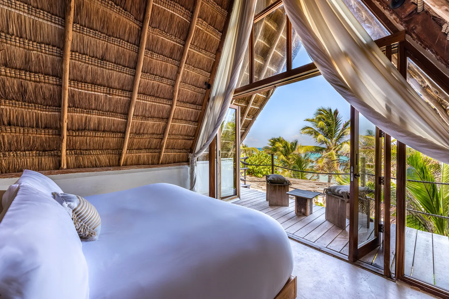 King bed under the palapa roof opening onto the ocean-view terrace — Sunrise Suite & Pelican Suite, La Valise Tulum