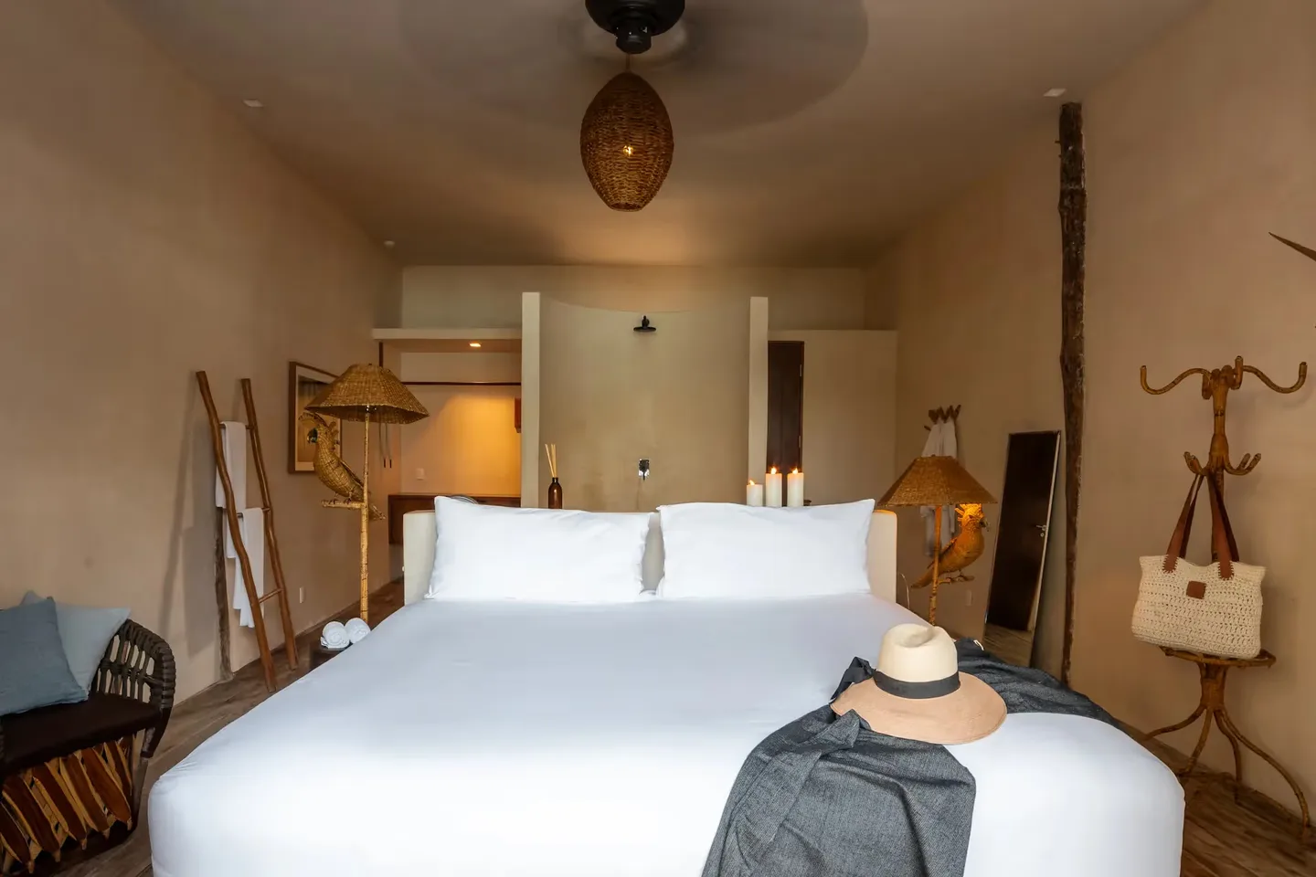 Interior de dormitorio de lujo en el hotel La Valise Tulum con una gran cama de madera, decoración boho-chic y ventilador de techo.