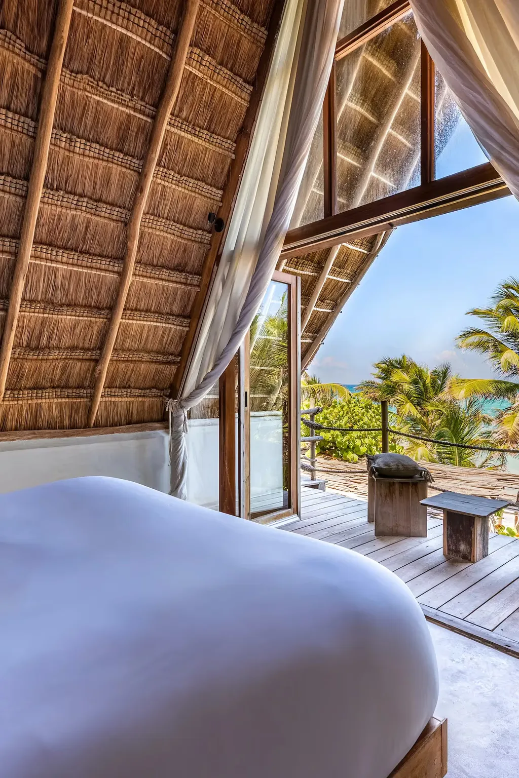 Vista panorámica desde la cama de una suite de lujo en el hotel La Valise Tulum, que se abre a una terraza privada y al océano turquesa en México.
