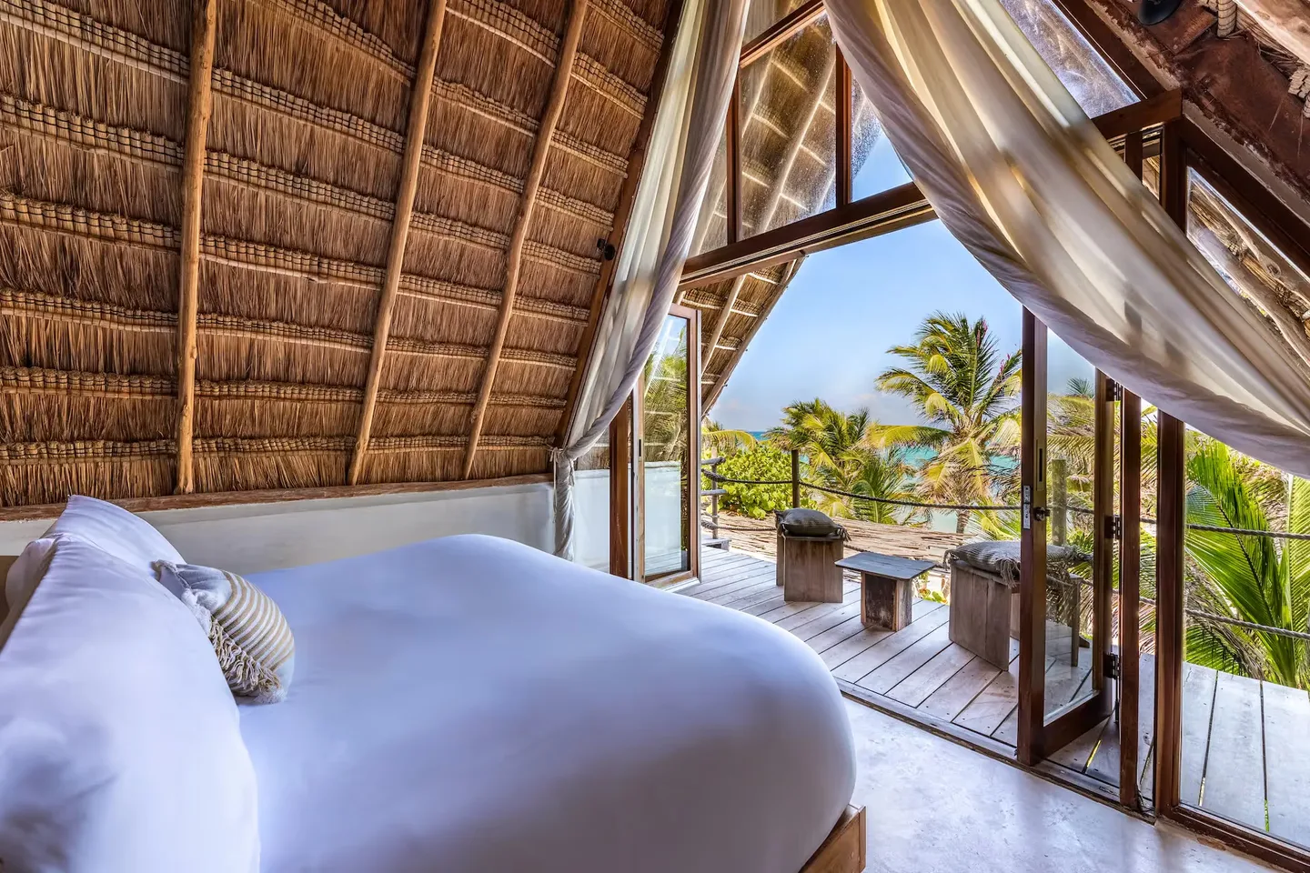 Vista panorámica desde la cama de una suite de lujo en el hotel La Valise Tulum, que se abre a una terraza privada y al océano turquesa en México.