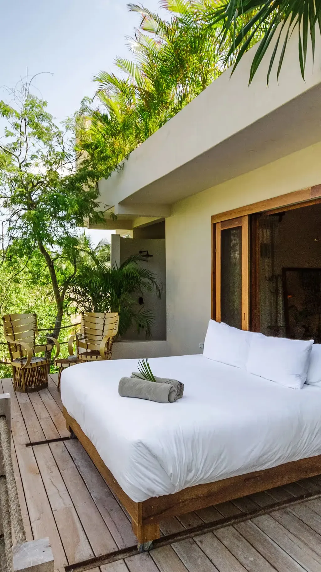 Cama al aire libre en una plataforma de madera en el hotel La Valise Tulum, rodeada de vegetación tropical de la selva.