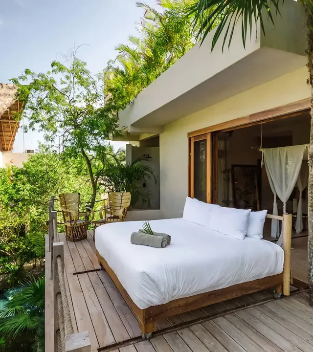 Cama al aire libre en una plataforma de madera en el hotel La Valise Tulum, rodeada de vegetación tropical de la selva.