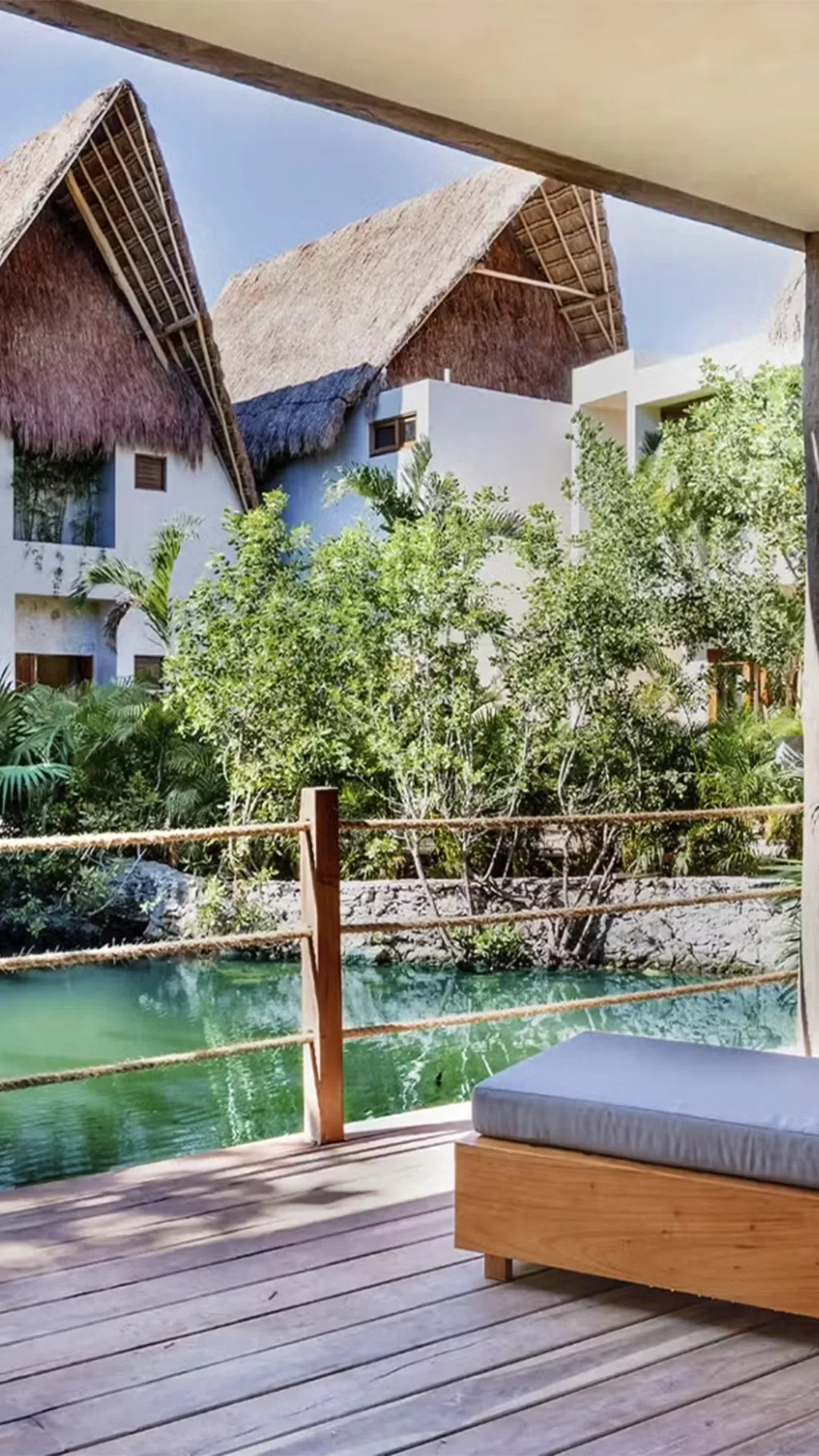 Cama exterior icónica en una terraza de madera rodeada de selva tropical en el hotel La Valise Tulum, México.
