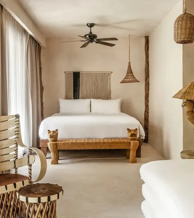 Suite elegante con cama king-size, sillón tejido y luz de ratán en La Valise Tulum.
