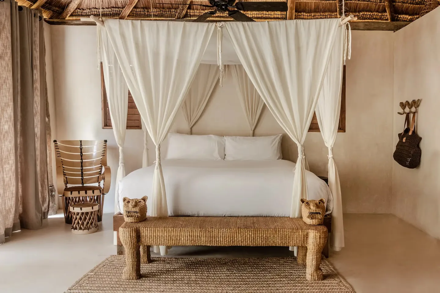 Dormitorio lujoso en el hotel La Valise Tulum con una cama con dosel blanca, cortinas elegantes y decoración artesanal en México.