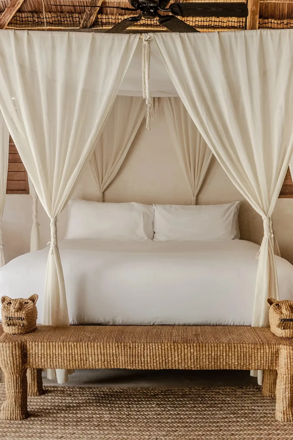 Dormitorio lujoso en el hotel La Valise Tulum con una cama con dosel blanca, cortinas elegantes y decoración artesanal en México.