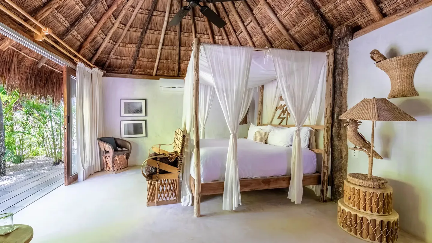 Habitación de hotel de lujo con acceso a la terraza y diseño artesanal en La Valise Tulum, México.