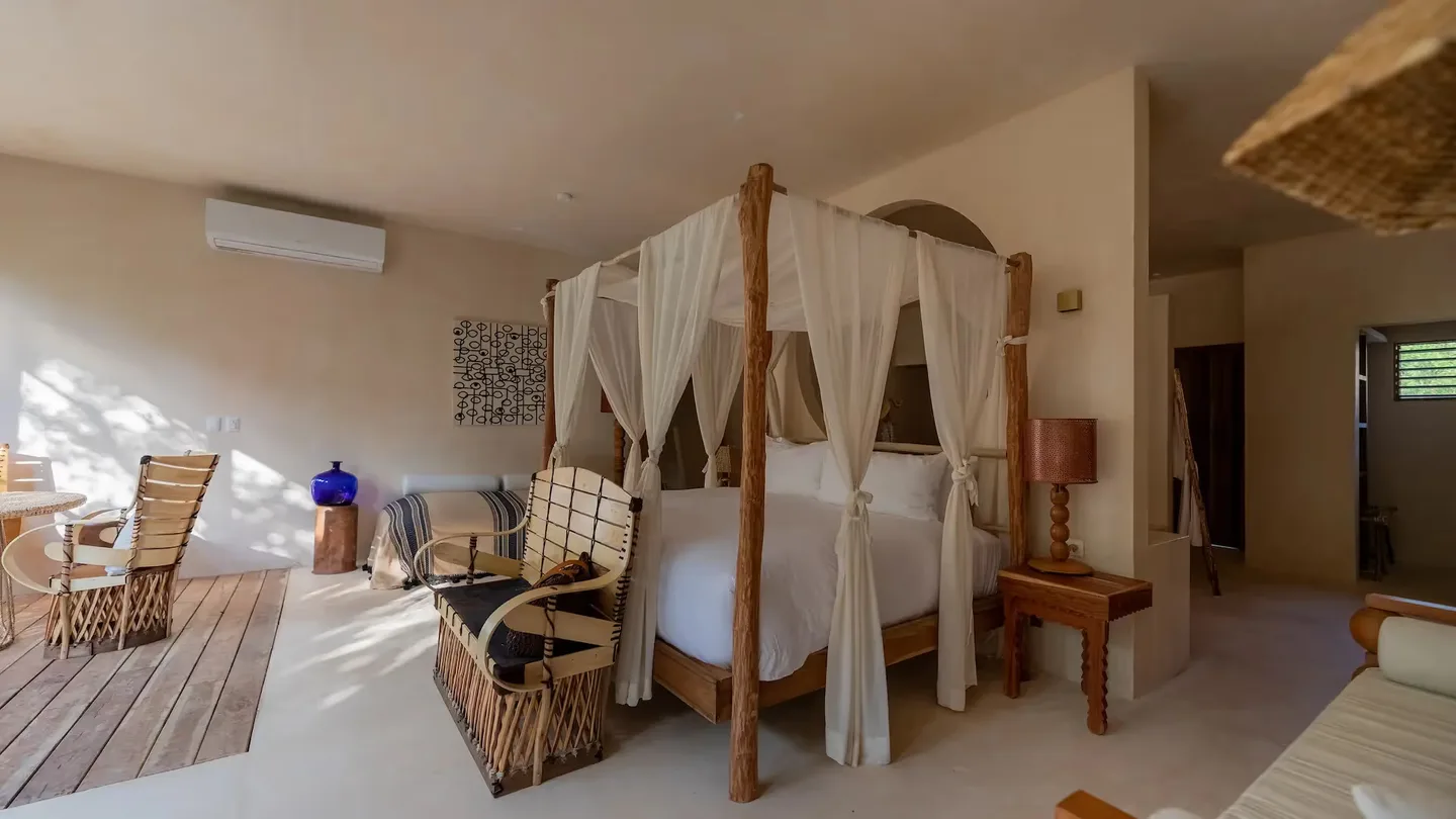 Habitación de lujo con cama con dosel de cuatro postes y ropa de cama blanca en el hotel La Valise Tulum, México.