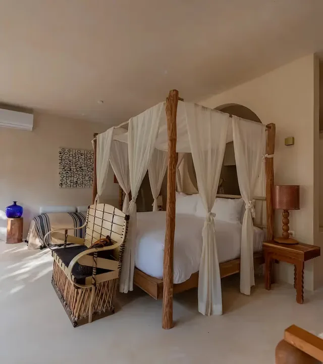 Habitación de lujo con cama con dosel de cuatro postes y ropa de cama blanca en el hotel La Valise Tulum, México.