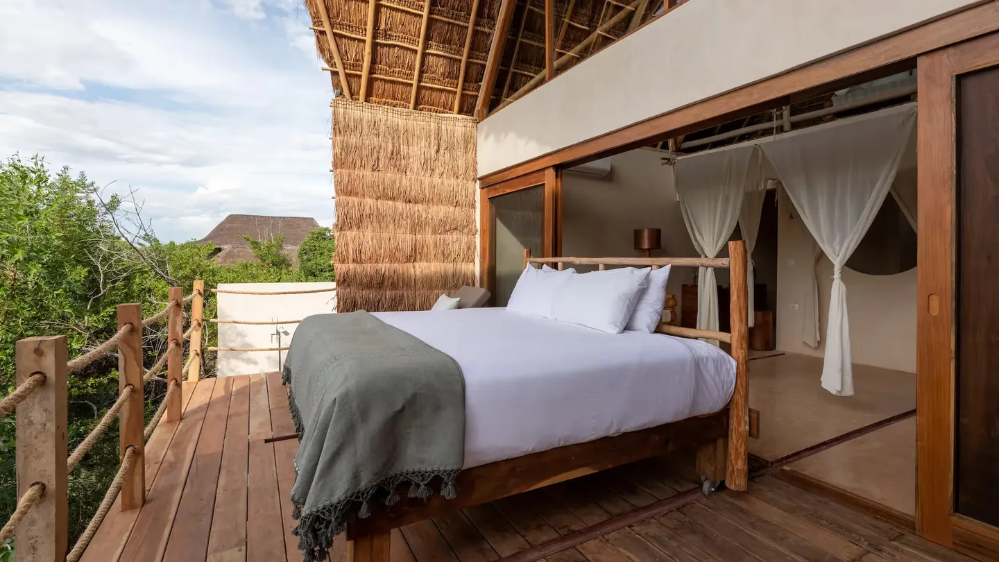 Terraza panorámica en La Valise Tulum con una cama al aire libre y arquitectura tradicional de madera.