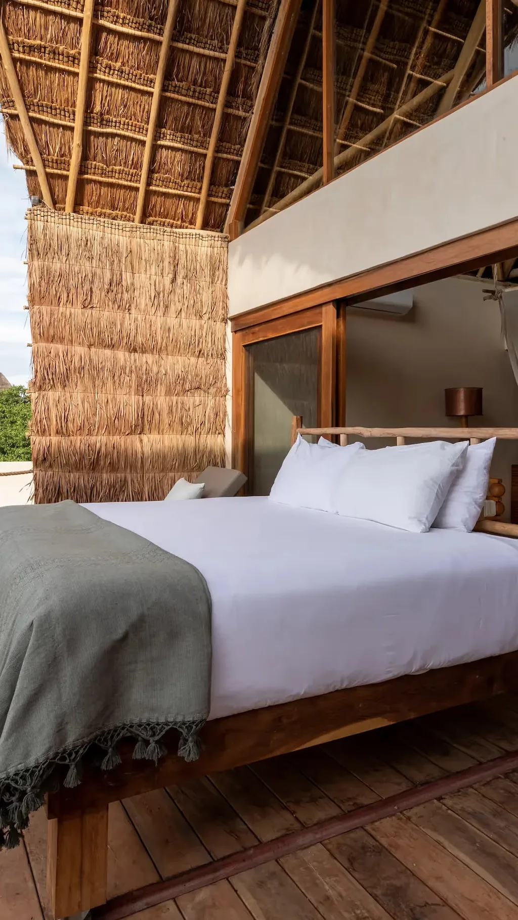 Terraza panorámica en La Valise Tulum con una cama al aire libre y arquitectura tradicional de madera.