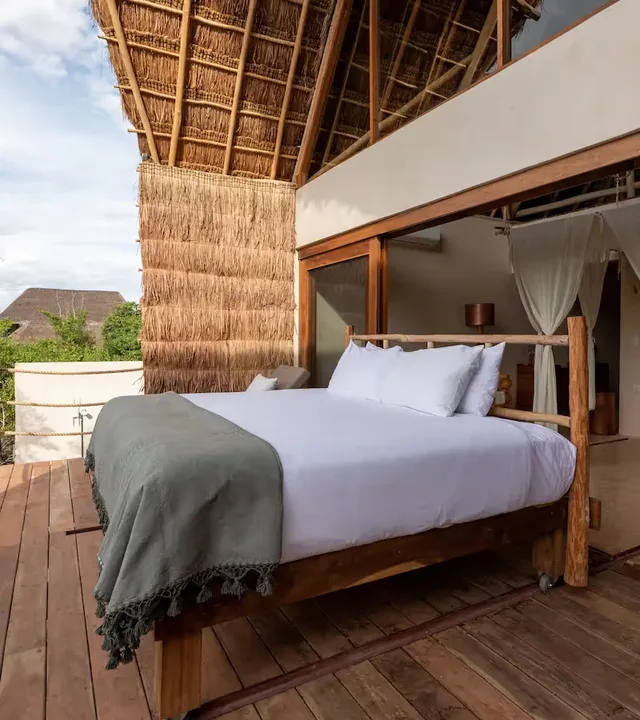 Terraza panorámica en La Valise Tulum con una cama al aire libre y arquitectura tradicional de madera.